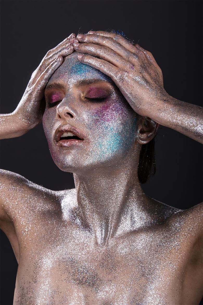 Fashion model with bright makeup and colorful glitter and sparkles on her face and body..jpg